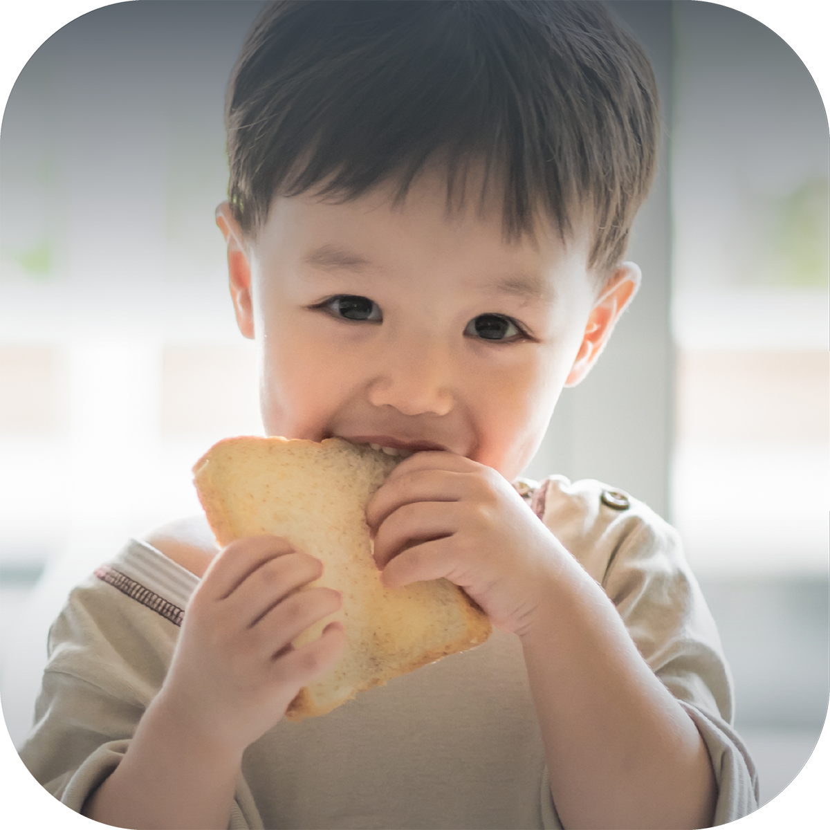 A Child Smiling while Taking a Bite of Bread