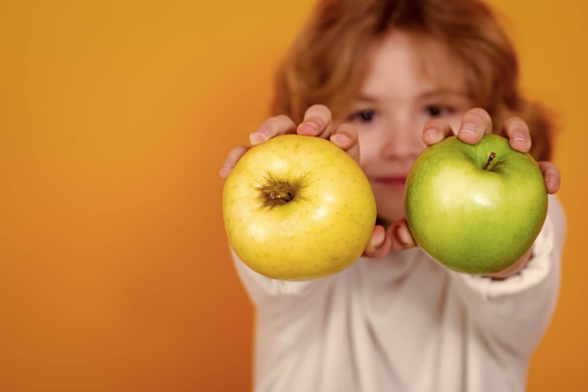 Feed to lead, young toddler with a yellow and green apple